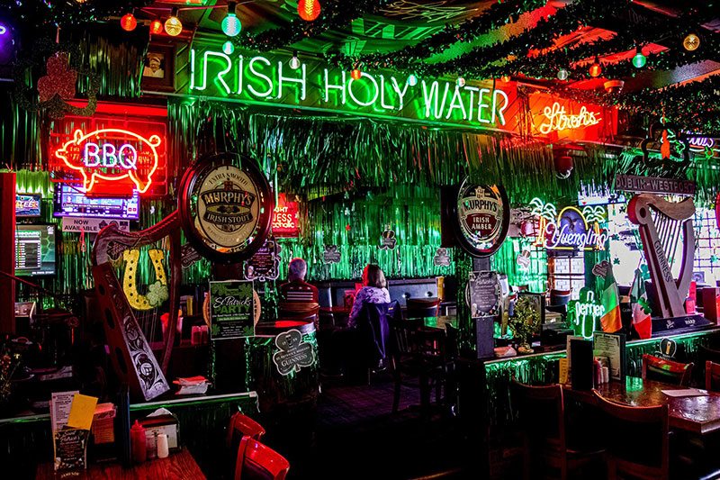 Inside of an Irish pub with neon signs and beer signs throughout the pub.