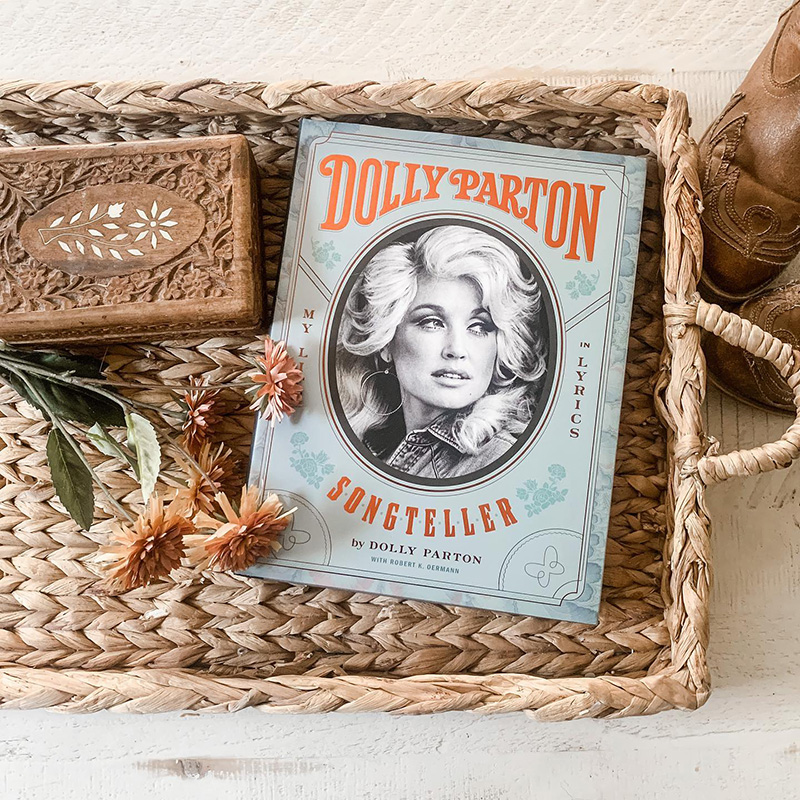 Wicker basket with dried florals and a book that reads "Dolly Parton Songteller".